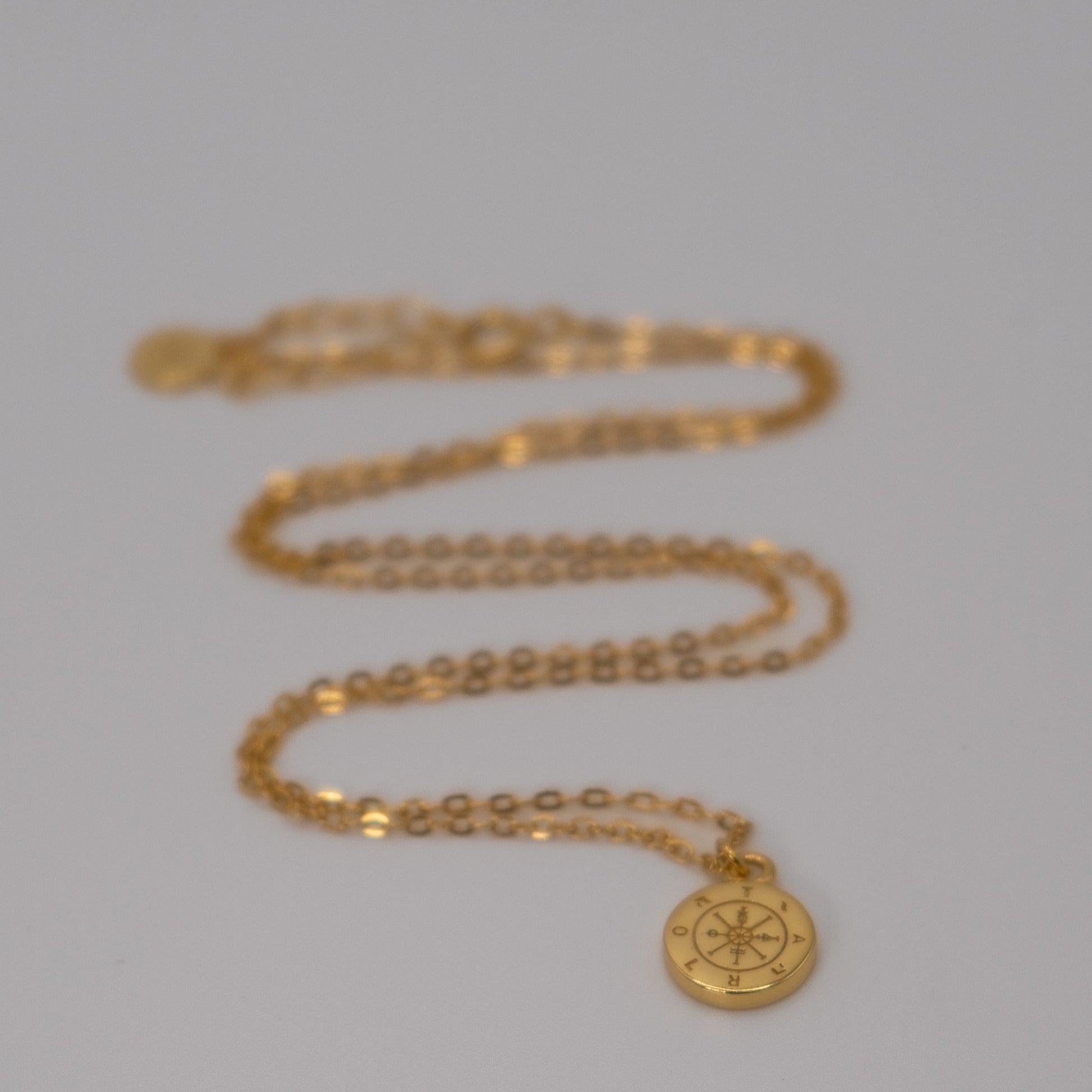 Lula Sea Jewellery journey pendant necklace, in 18k gold vermeil, necklace features a tiny golden compass hanging from a delicate gold chain. View of necklace on face surface Lula Sea Jewellery New Zealand 